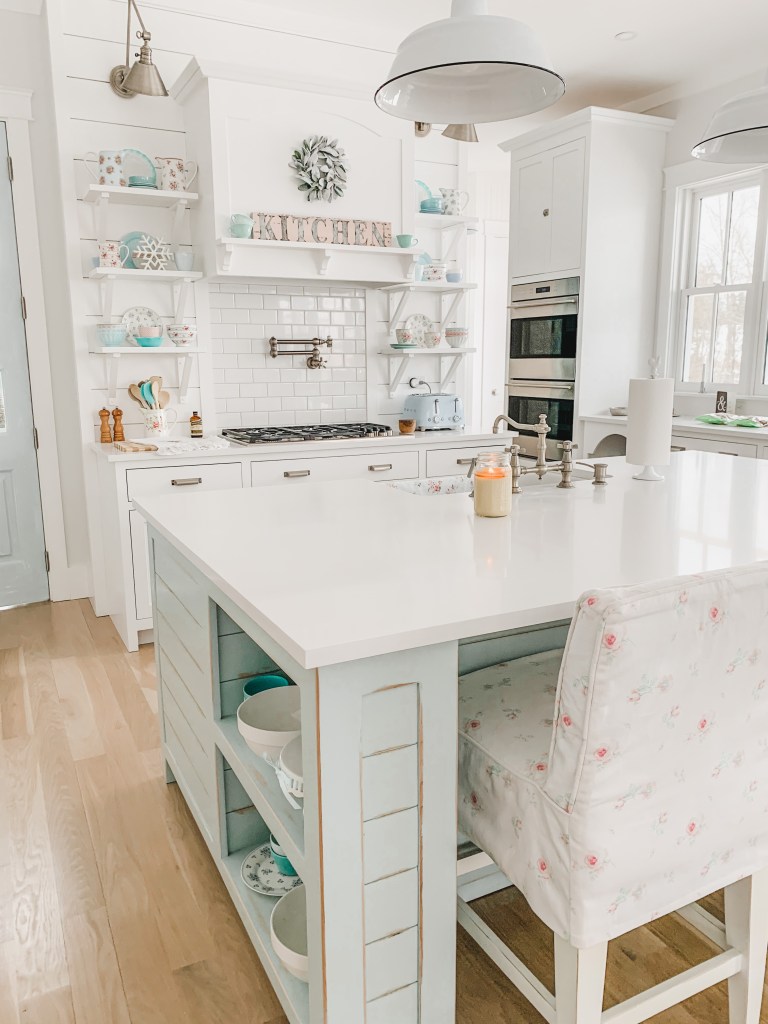 Blue kitchen island with white bar stools
