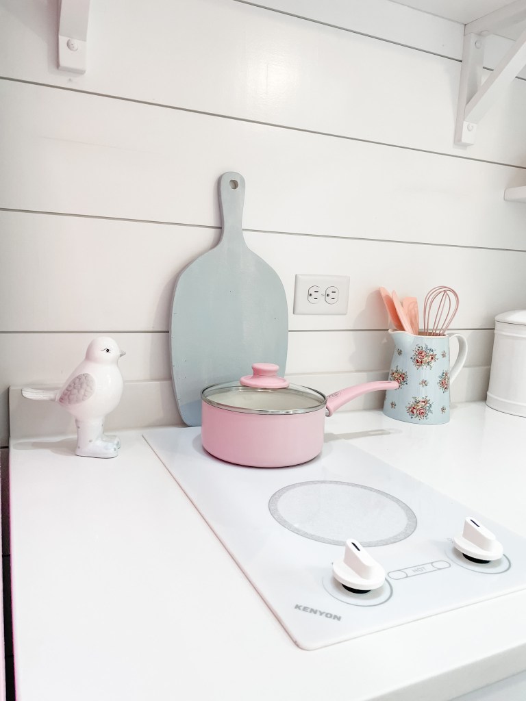 cooktop with pink pan and blue cutting board