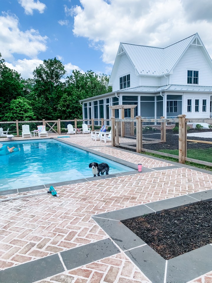 in-ground pool with a white farmhouse