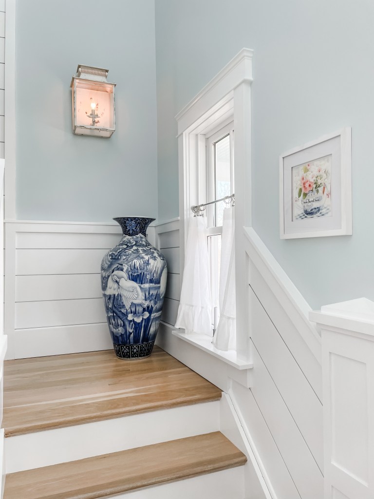 white shiplap staircase with art and window